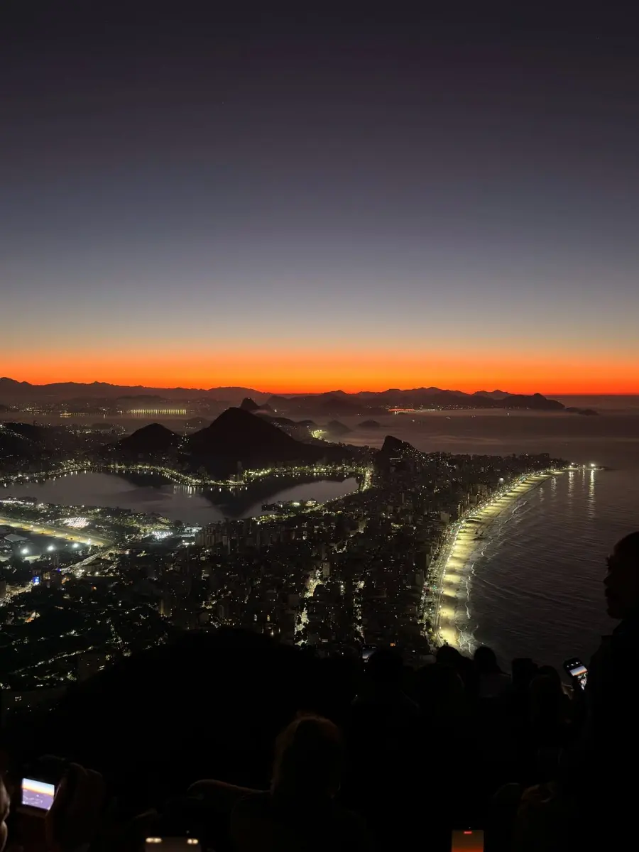 Rio still lit up before dawn, seen from the summit of Dois Irmaos, with the first orange light on the horizon