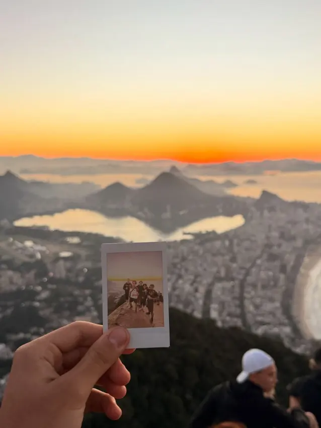 A polaroid of the group held up against the sunrise seen from the summit of Dois Irmaos
