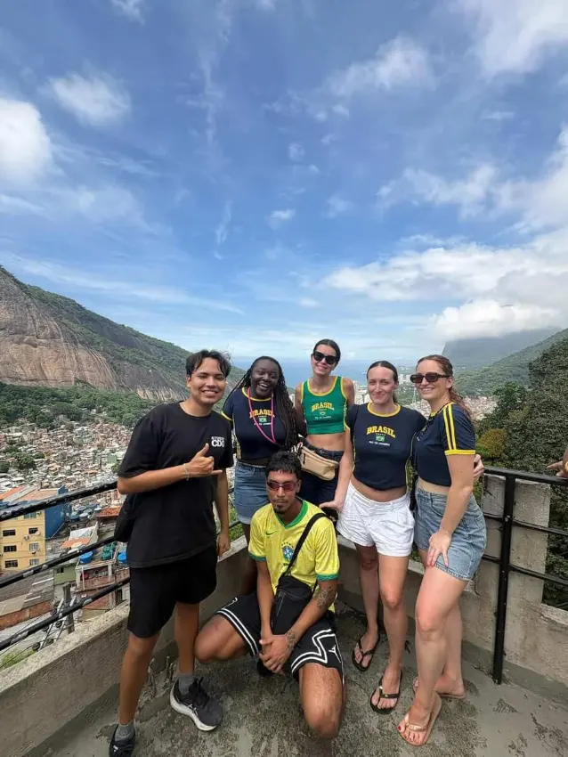 A larger group of six travellers and their guide posing at a Rocinha viewpoint